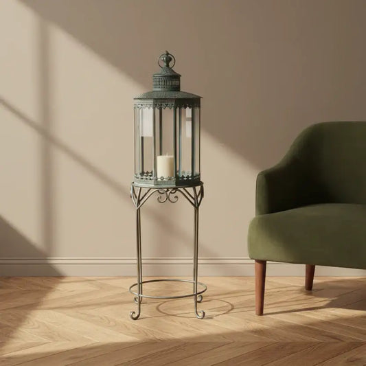 Decorative lantern on a stand next to a green armchair in a room with wooden flooring and beige walls.