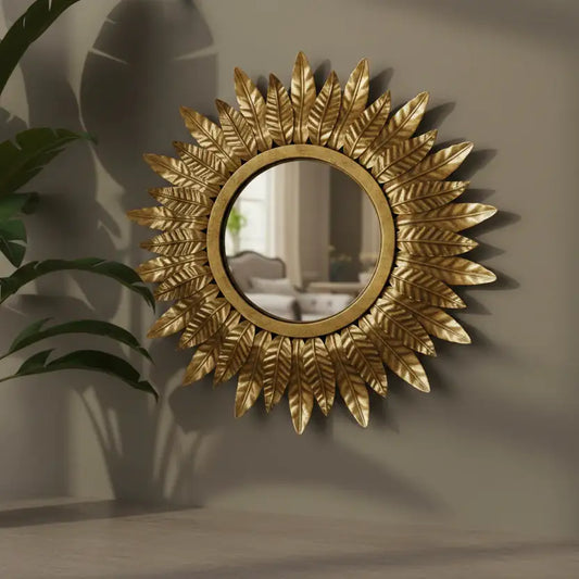 Decorative gold mirror with leaf-like patterns on a wall.