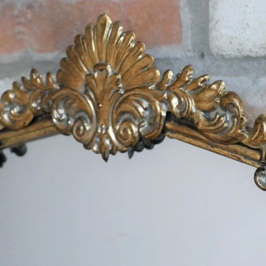 Decorative gold mirror with intricate designs on a white background