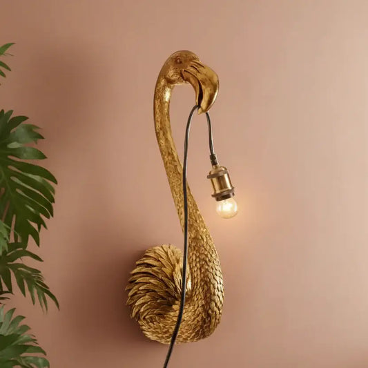 Gold flamingo wall light fixture on a pink background
