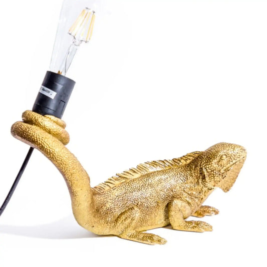 Gold iguana-shaped lamp with a light bulb on a white background