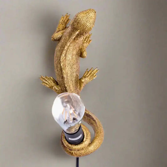 Gold lizard-shaped wall light fixture on a white background