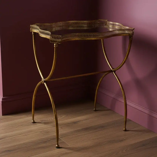 Gold metal console table against a purple wall