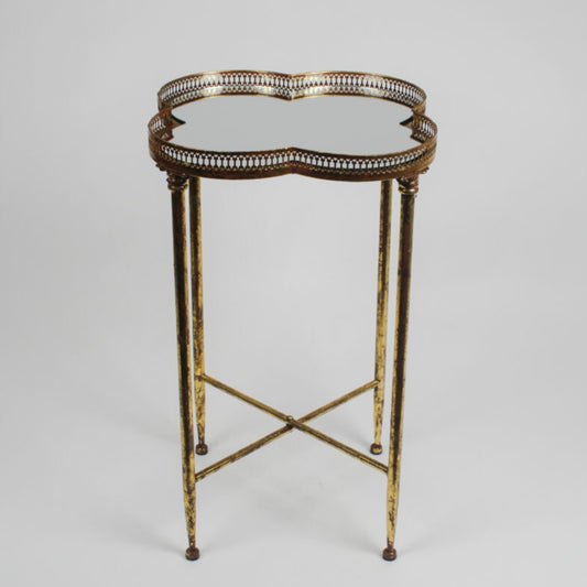 Decorative side table with gold metal frame and glass top on a gray background