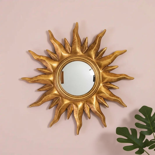 Gold sun-shaped mirror on a pink background
