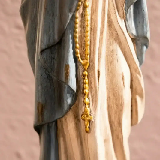 Gold rosary hanging on a wooden surface with a blurred background