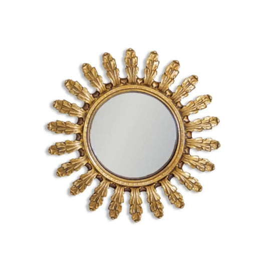Decorative gold sunburst mirror on a white background