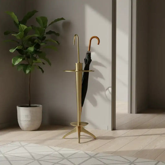 Gold umbrella stand with a plant and open umbrella in a room with wooden floor and white walls.