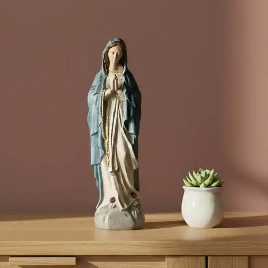 Statue of a religious figure on a table with a candle and decorative items.