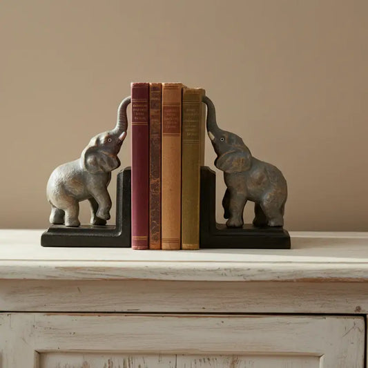 Elephant bookends holding books on a wooden surface with a beige wall background