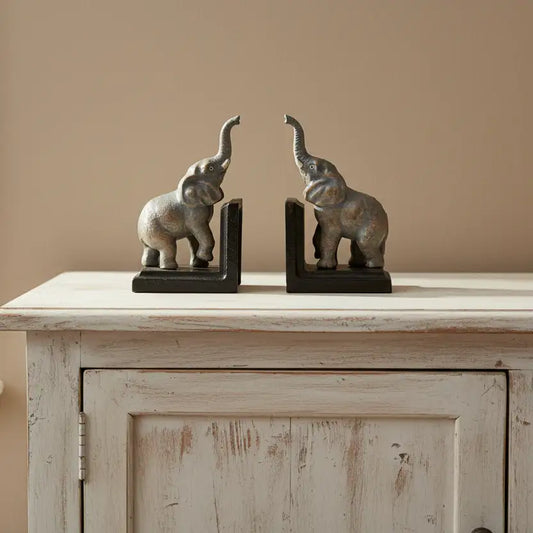 Bronze elephant bookends on a wooden cabinet against a beige wall