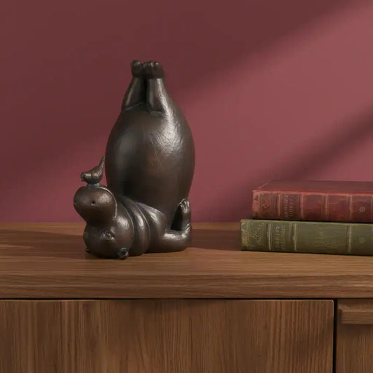 Bronze sculpture of a cat and mouse on a wooden surface with books against a red background