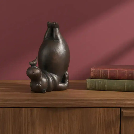 Bronze sculpture of a cat and mouse on a wooden surface with books against a red background