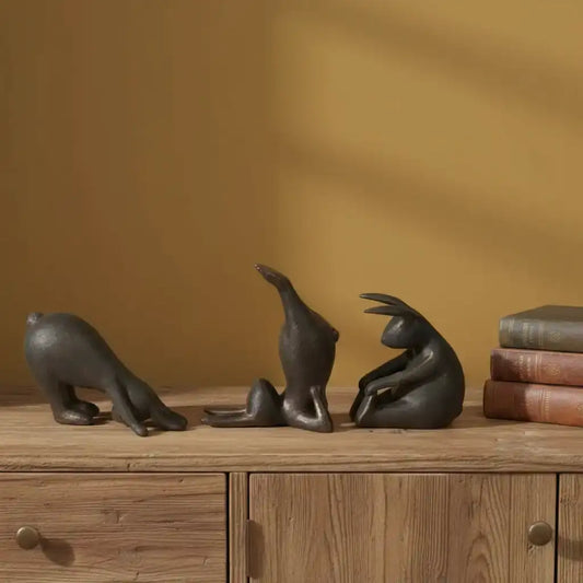 Three black animal sculptures on a wooden surface with a warm brown background