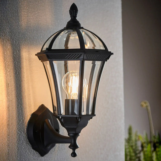 Black outdoor wall light fixture on a textured wall with a blurred background