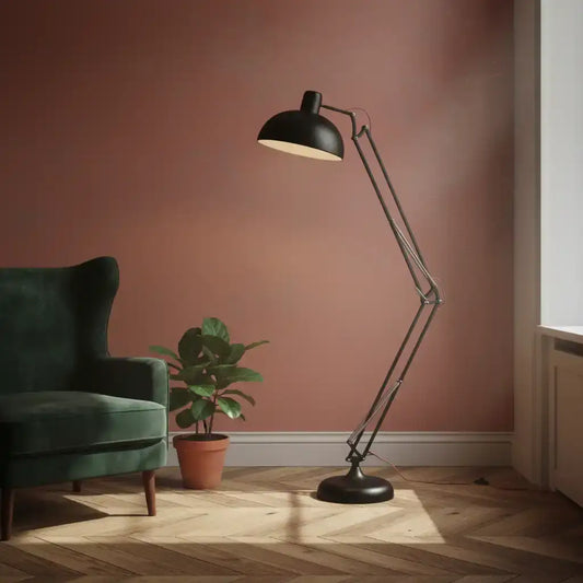 Black floor lamp in a room with a green armchair and plant on a wooden floor.