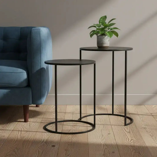 Two black side tables with a plant in a living room setting.