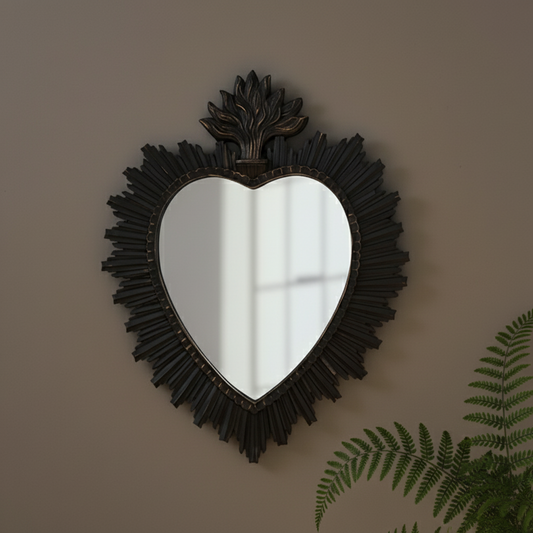 Heart-shaped mirror with decorative frame on a wall with a plant in the corner