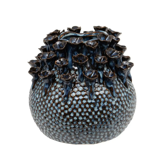 Decorative ceramic vase with textured surface and floral-like top on a white background