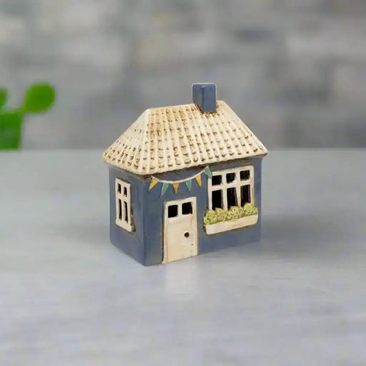 Small model of a house with a blue base and beige roof on a white background