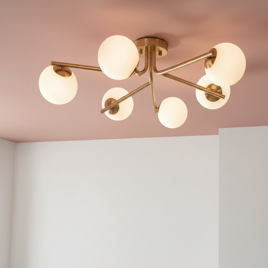 Modern ceiling light fixture with six spherical glass shades on a pink and white wall background