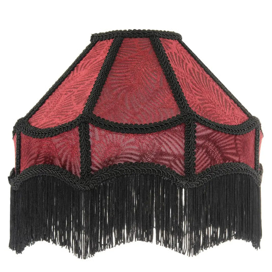 A vintage-style fabric lampshade with a red patterned body, black braided trim, and a long black fringe along the bottom edge, shown against a plain white background.