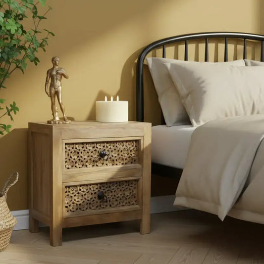 Wooden nightstand with decorative items next to a bed in a bedroom setting.