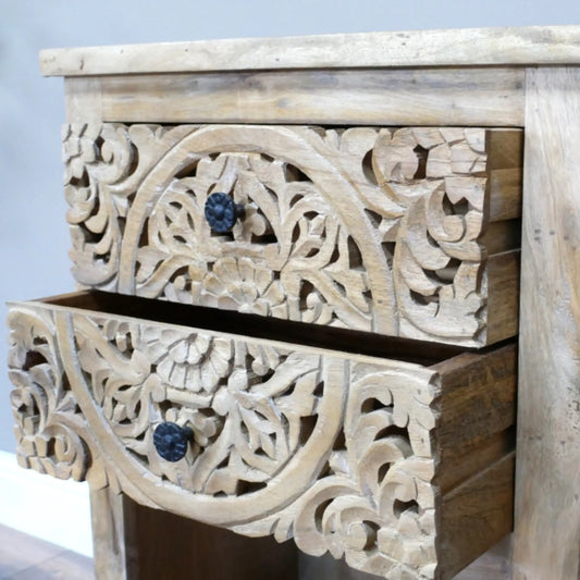 Wooden drawer with intricate carvings and dark knobs on a light background