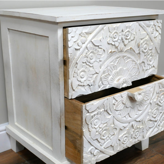 White wooden dresser with intricate carvings on a plain background