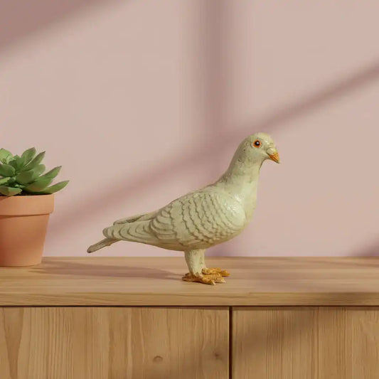 Decorative pigeon figurine on a wooden surface with a pink background