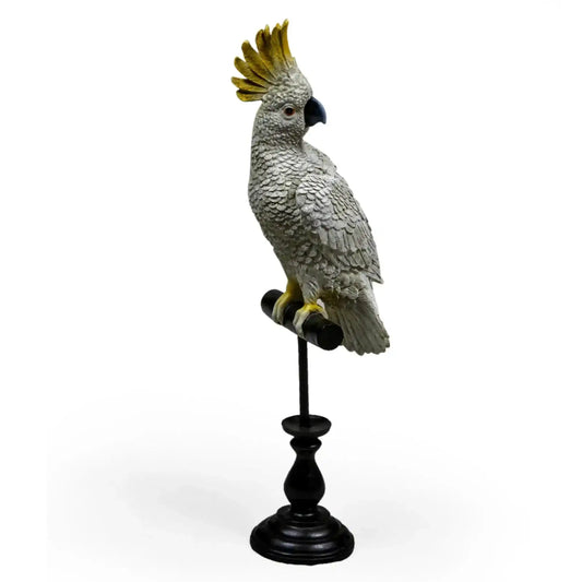 Gray parrot figurine with a yellow crest on a black stand against a white background