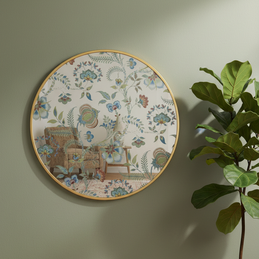 Round decorative wall plate with a botanical and floral pattern, featuring a vintage-style illustration of an armchair and a small table. The plate has a gold-toned rim and is mounted on a light sage green wall next to a green plant.
