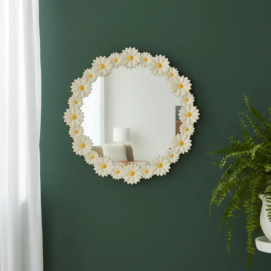 Round floral mirror with white flowers and yellow centers on a green wall.