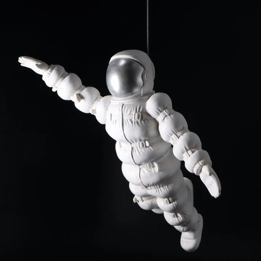 White astronaut figure hanging against a black background