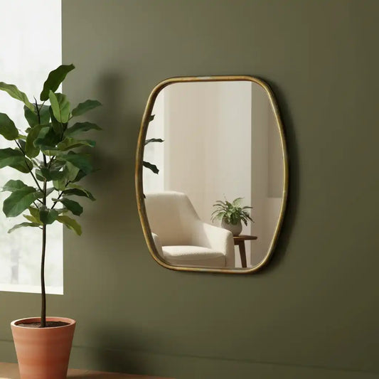 Gold-framed mirror on a green wall with a plant to the left