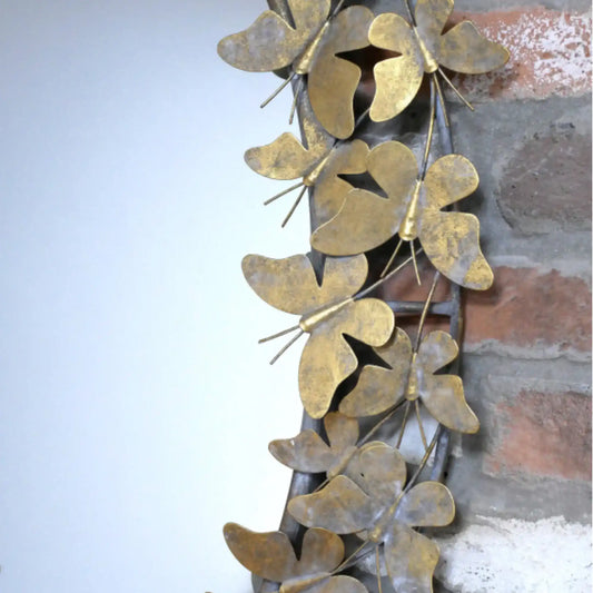 Decorative metal wall art with butterfly designs on a stone wall background