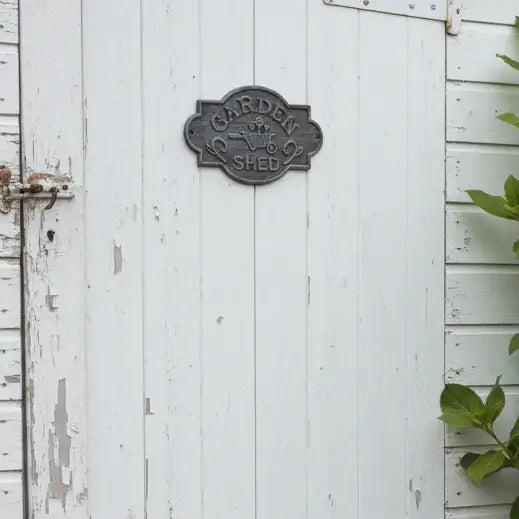 Weathered white wooden door with a metal 'Garden Shed' sign.