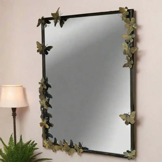 Decorative mirror with butterfly design on a wall next to a lamp and plant.