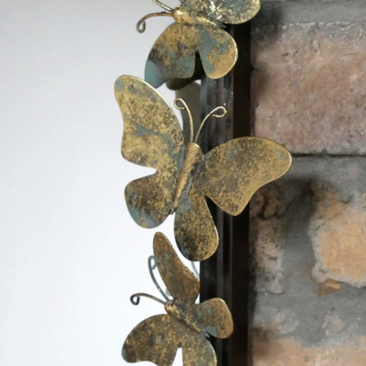 Decorative metal butterflies on a fireplace mantle.