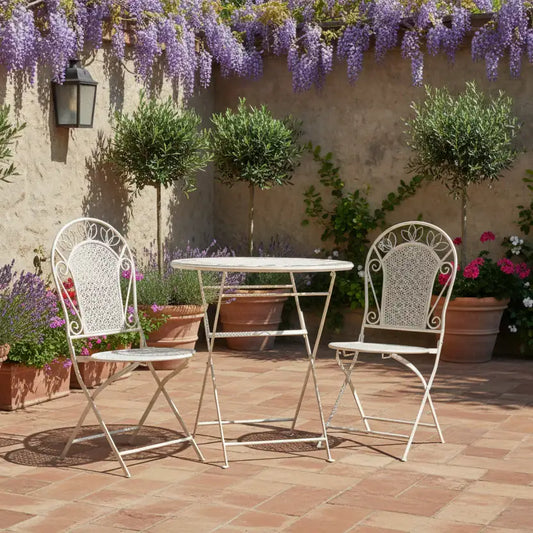 Outdoor patio set with table and chairs under a wisteria vine on a stone wall.