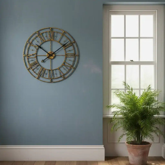 Decorative wall clock on a blue wall with a window and plant in the background
