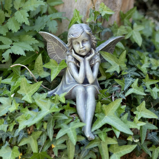 Statue of a fairy sitting among green leaves
