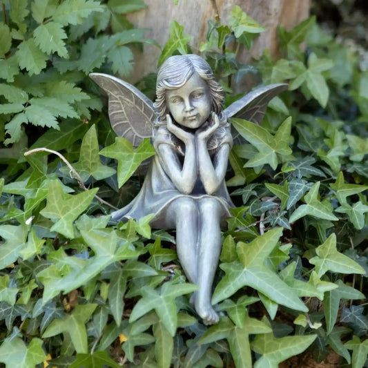 Statue of a fairy sitting among green leaves
