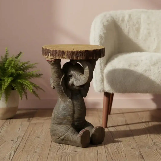 Wooden side table shaped like an elephant with a plant and chair in the background