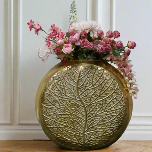 Decorative gold vase with floral arrangement on a gray surface