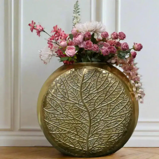 Decorative gold vase with floral arrangement on a gray surface