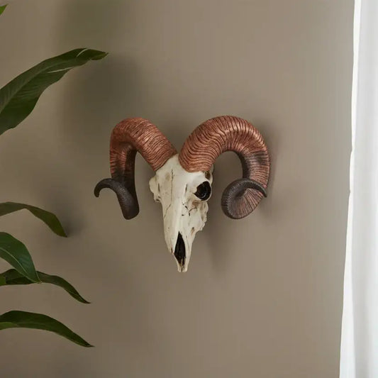 Decorative ram skull with large curved horns on a beige wall.