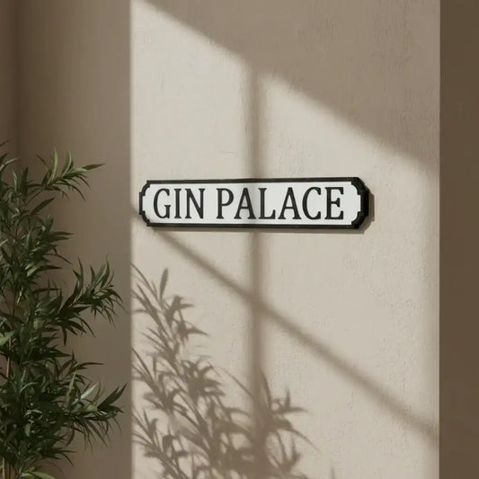 Decorative sign with 'Gin Palace' text on a beige wall with plant shadows.