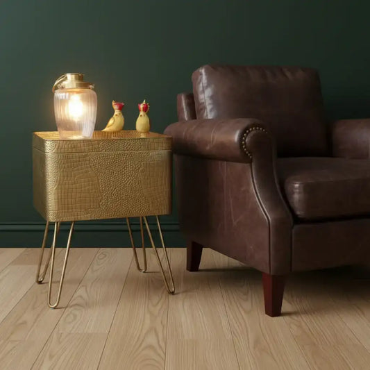 Gold textured side table with a lamp and decorative birds on a gray wall background