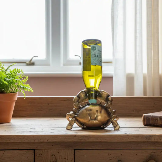 Decorative bottle holder shaped like a crab on a wooden surface with a window in the background.